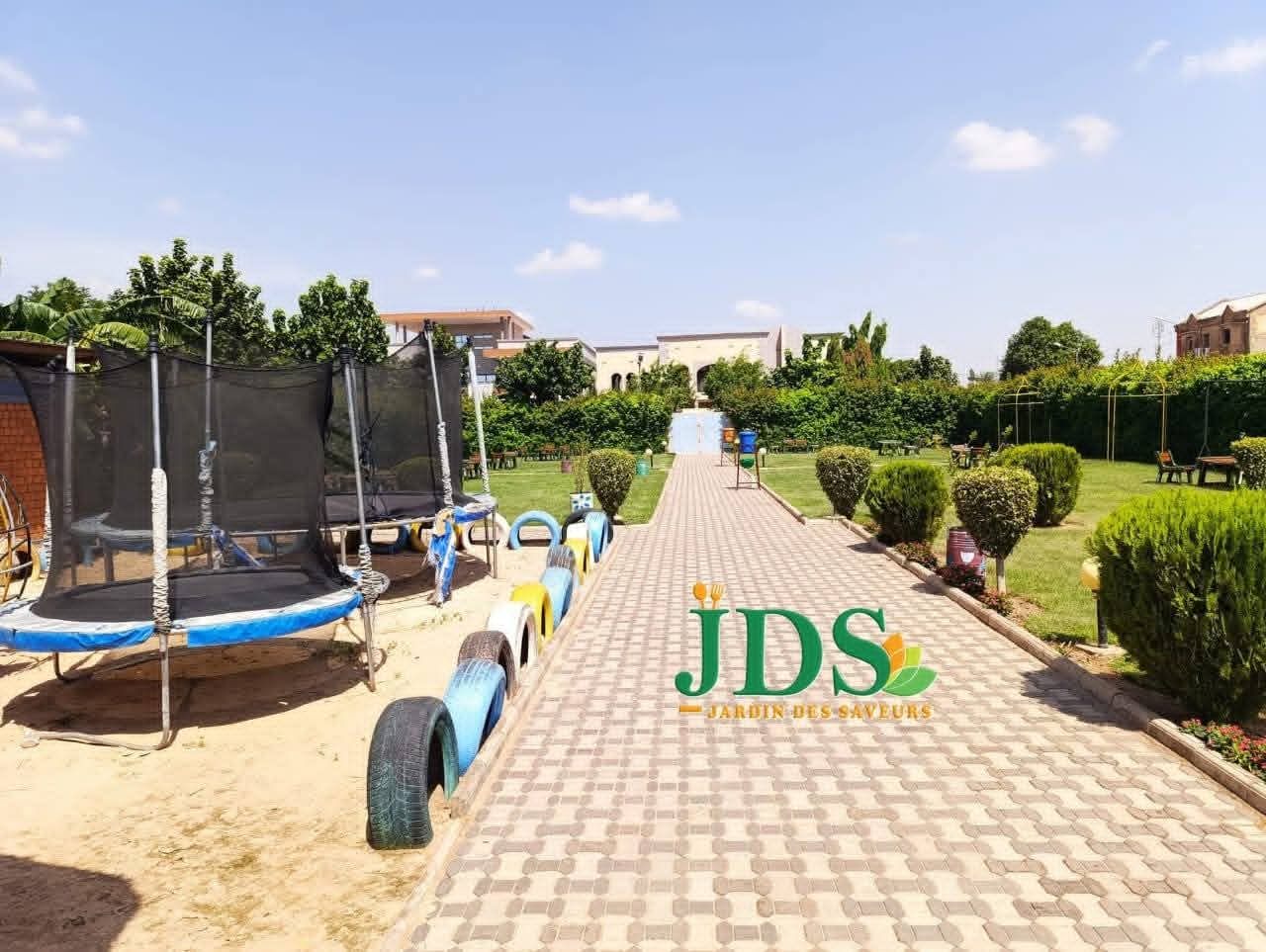 Allée pavée menant à l'aire de jeux avec trampolines pour enfants